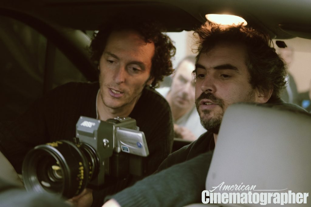Cinematographer Emmanuel Lubezki and Alfonso Cuarón are seated in the back of a car with a small digital camera facing outward set up between them.