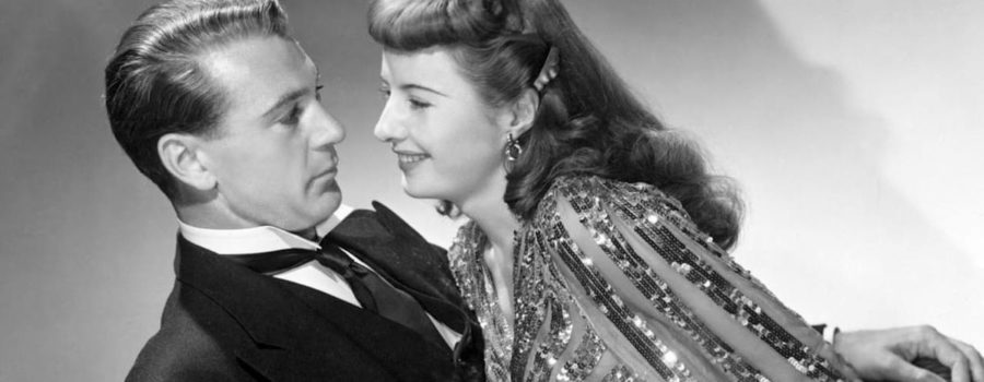 A black-and-white image of a woman in a sequined dress (Barbara Stanwyck) leaning against a man in a tuxedo (Gary Cooper).