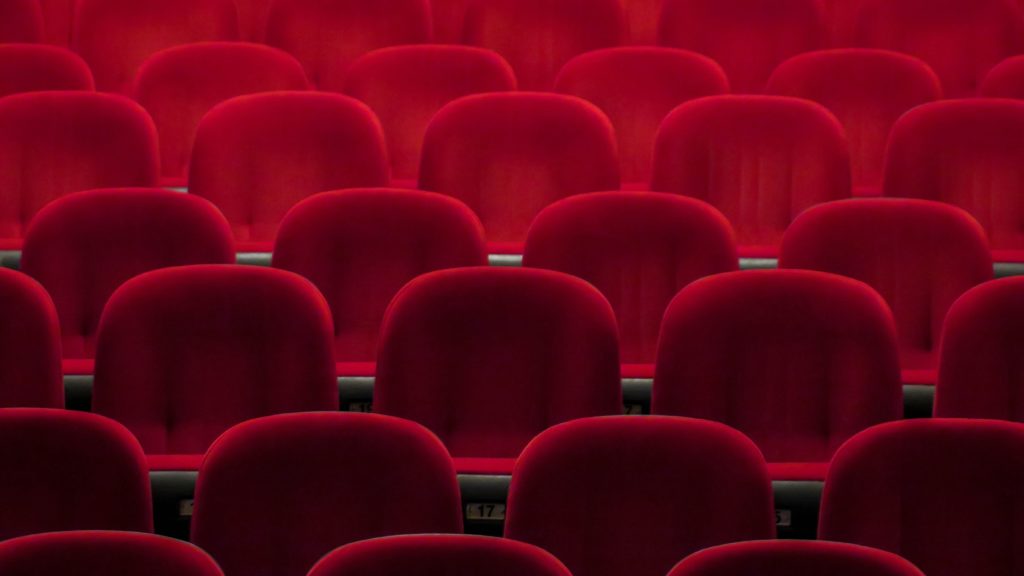 Several rows of empty red chairs in a theater. 