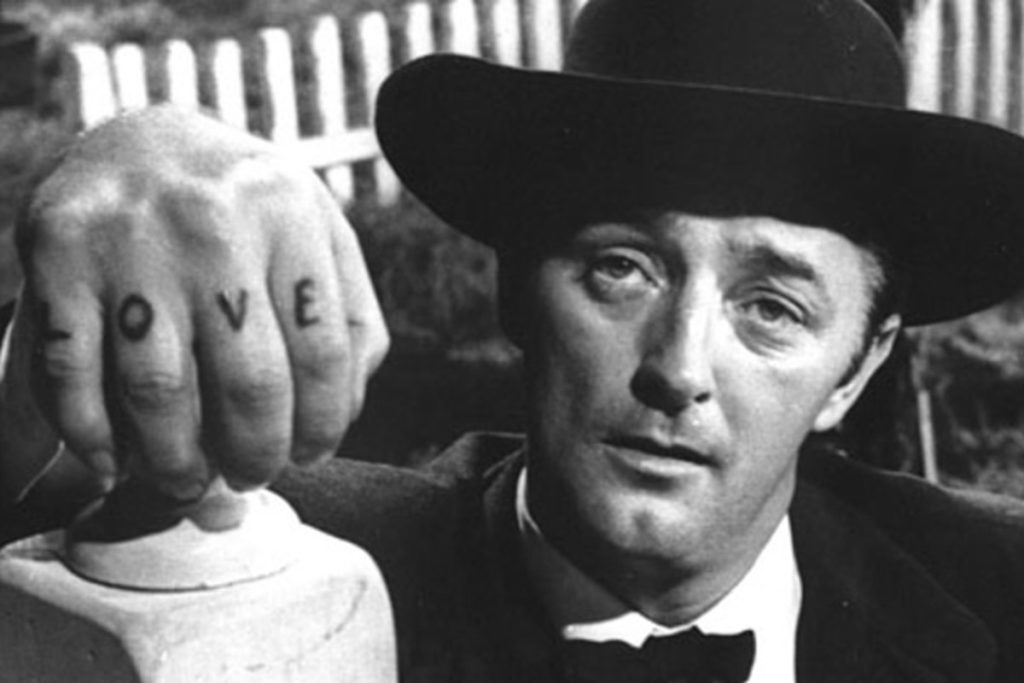 A black-and-white image of a man (Robert Mitchum) in a black hat staring near the camera, the word "Love" tattooed on his fingers.