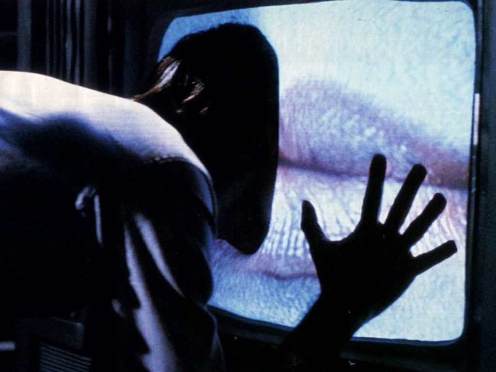 A human body enters a television screen that has a huge pair of lips broadcast on it.