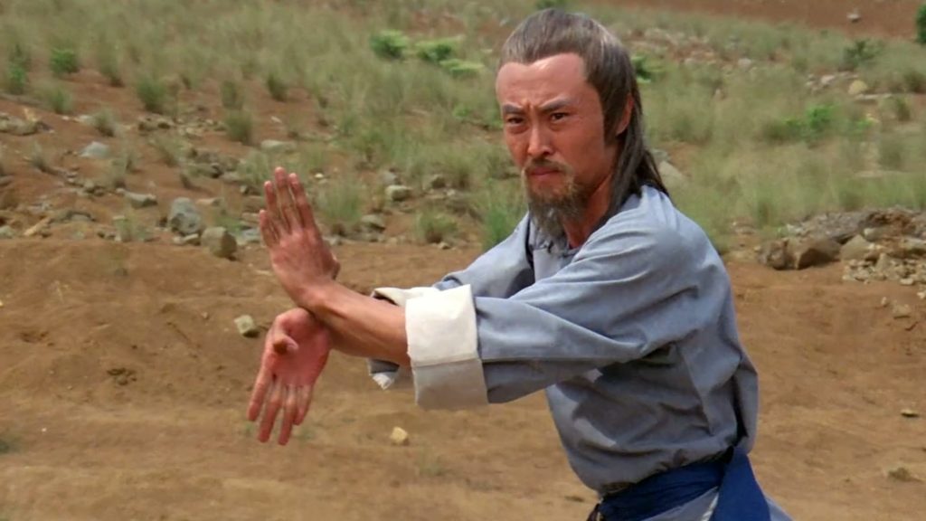 Jack Long as Shang-Kuan Cheng in 7 Grandmasters, wearing a blue outfit and practicing martial arts in a field. 