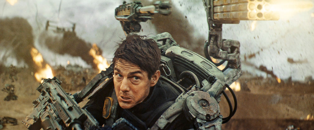 Tom Cruise wearing full armor and firing multiple guns in the film Edge of Tomorrow.