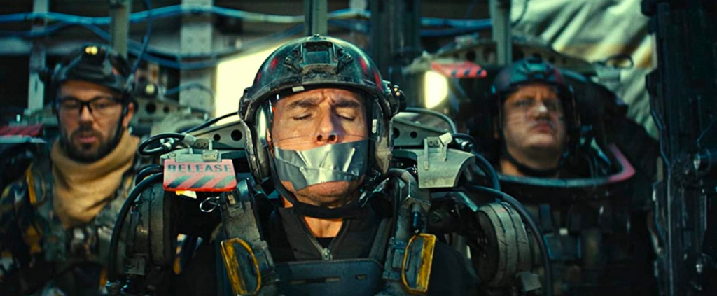 Tom Cruise wearing full armor and helmet, with duct tape over his mouth, about to be dropped from an airplane in the film Edge of Tomorrow.