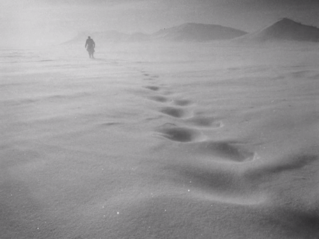 A lone human figure wanders through a wintry landscape. Shot from the film Letter Never Sent.