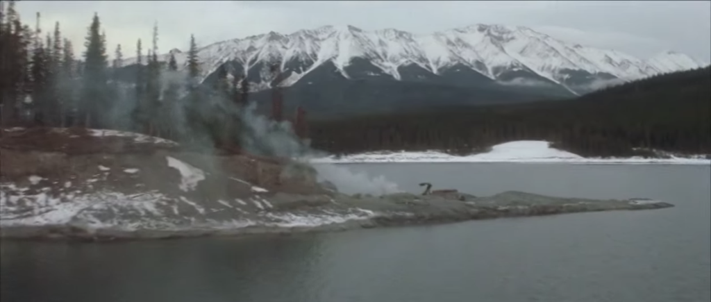 A lone figure waves a coat in the air in a wintry landscape. Shot from the film The Edge.