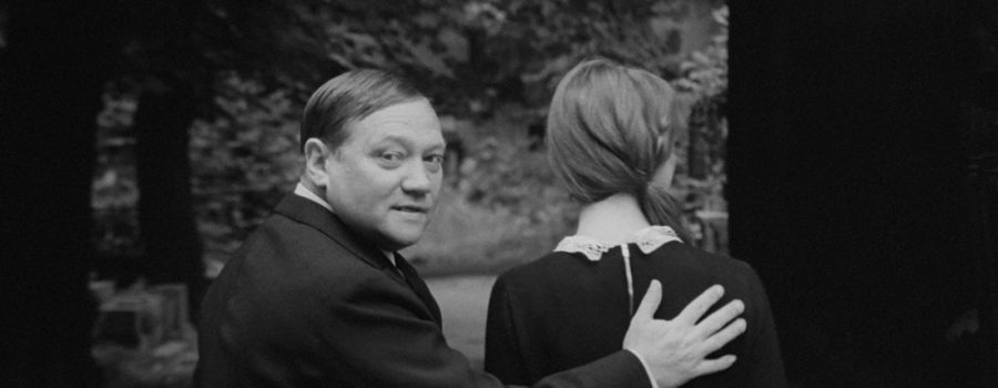 A man, Karel, places his hand on the back of a woman in the film "The Cremator."