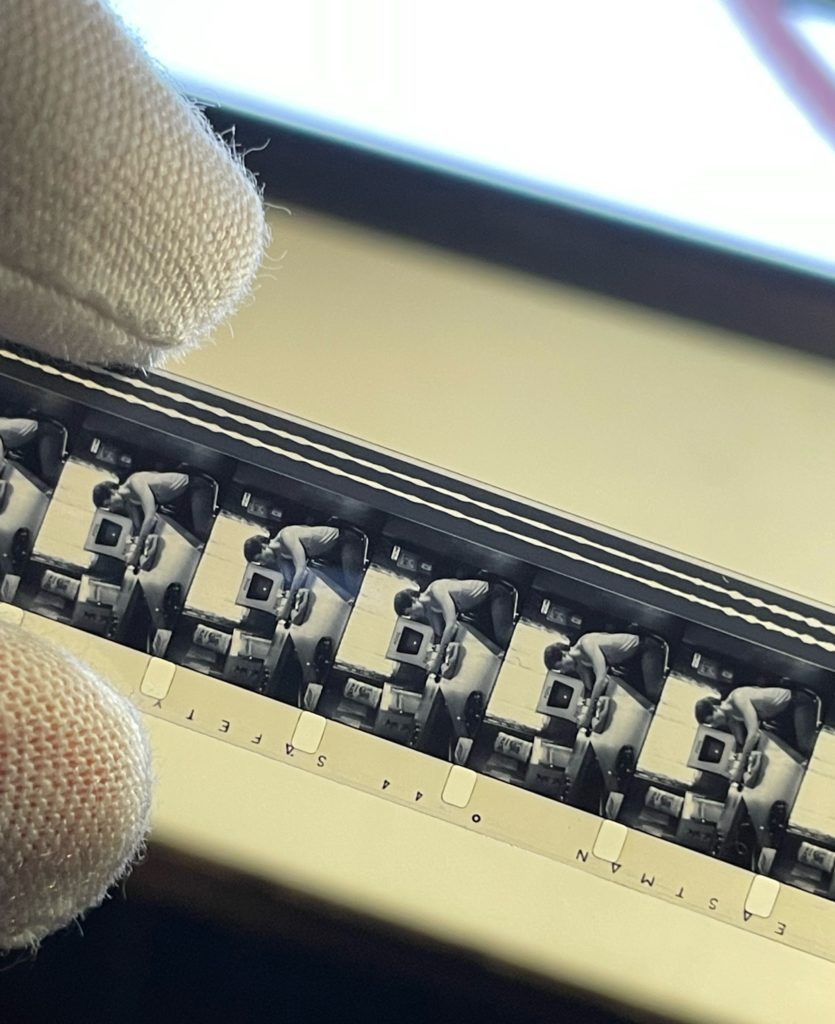 A gloved hand works on a celluloid film strip. 