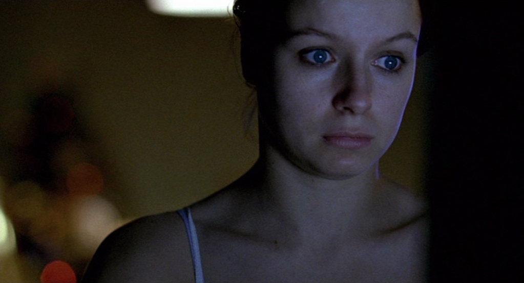 Samantha Morton as Morvern Callar facing the camera, looking at a computer screen. Her face is covered in the screen's blue glow. Her eyes are wide open and have bags underneath. Her expression is blank.