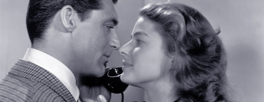 Medium close-up of T.R. Devlin, played by Cary Grant, and Alicia Huberman, played by Ingrid Bergman leaning in for a kiss while Devlin takes a phone call.
