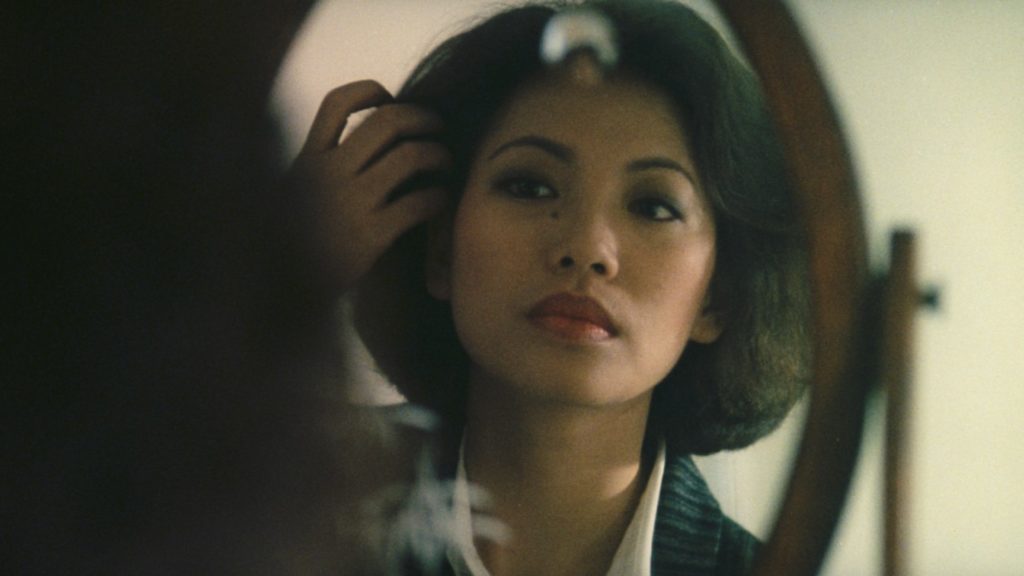 A woman (Tsai Chin) fixes her hair in a mirror in the film "Taipei Story." 