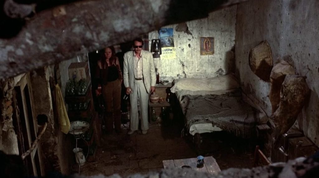 Bennie and Elita stand in the doorway of a room at a dilapidated motel.