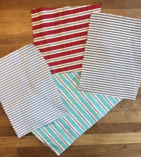 A picture of four fabric swatches. The one on the left is blue and white seersucker. The one on the top is red, white, and black seersucker. The one on the right is grey and white seersucker. The one on the bottom is aqua, white and black seersucker.