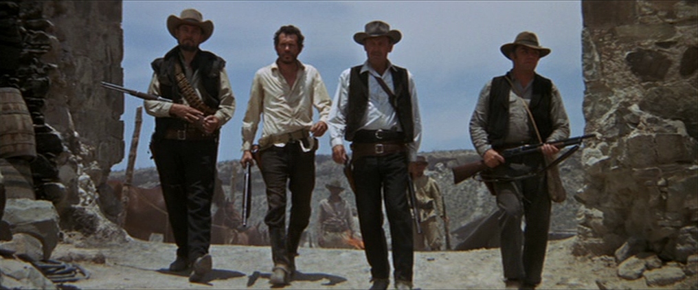 Four men dressed in western garb and carrying guns walking through a town in "The Wild Bunch."