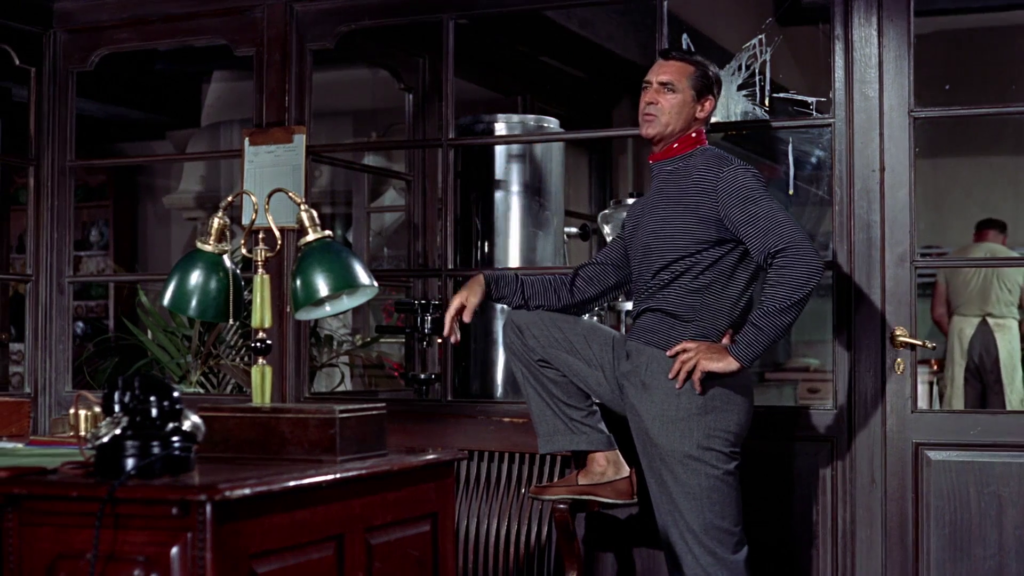Cary Grant in "To Catch a Thief" wearing a dark blue shirt with white stripes, a red scarf, and leather shoes.