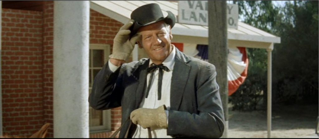 A picture of Joel McCrea on horseback, grinning and tipping his hat.