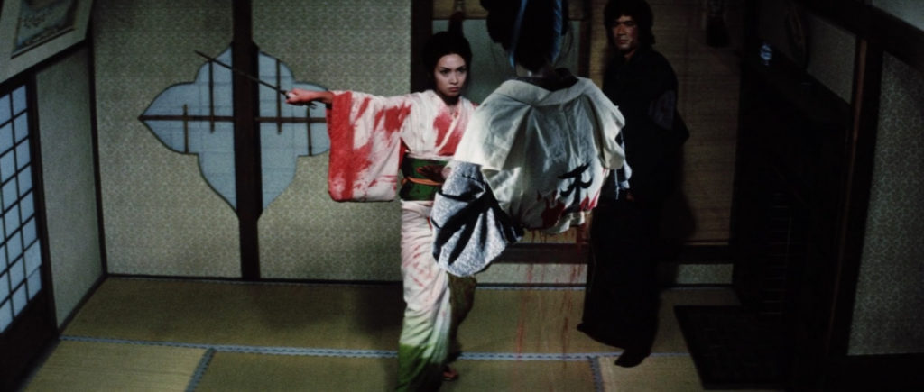 Two images of a blood-splattered Yuki, sword in hand, having just dismembered one of her foes who hangs lifeless from the ceiling before a stage curtain lowers in the foreground.
