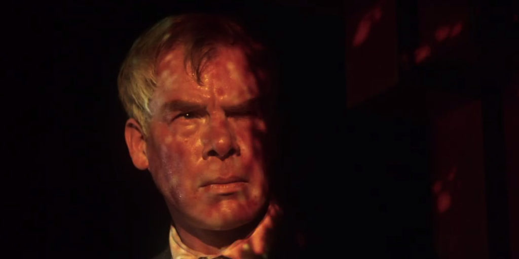 Walker grimaces as psychedelic colors are projected over his face in a nightclub.