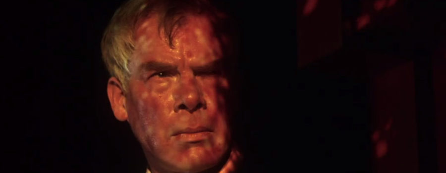 Walker grimaces as psychedelic colors are projected over his face in a nightclub.