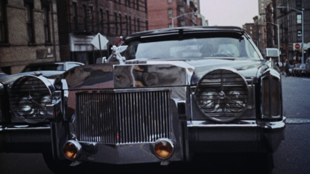 A close-up of the grille of a customized Cadillac Eldorado driving down a street in Harlem, New York.