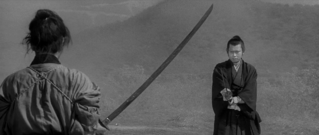 Ronin samurai Sakon Shiba faces off against the village magistrate. Shiba is on the left, holding a large sword. The magistrate is holding a smaller sword. There is a wooded mountain in the background.