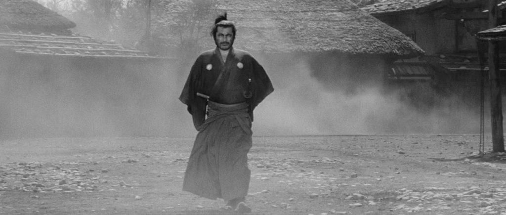 Toshiro Mifune as Sanjuro walks down a dusty village street in Yojimbo.