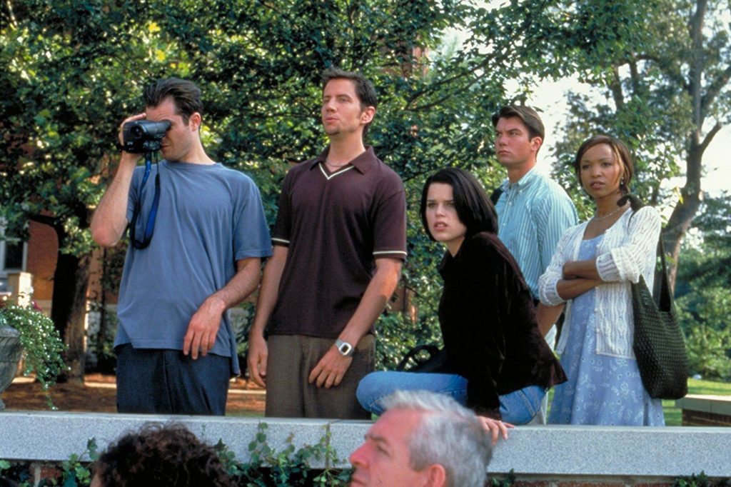 Mickey, holding a video camera (left), Randy (second to Left), Sidney (Center), Derek (Second to right), and Hallie (right) are standing on a college campus, watching something off-screen