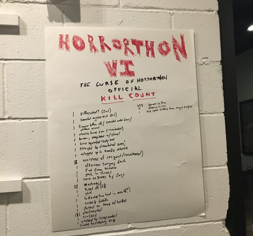 A poster board with the words "Horrorthon VI: The Curse of Horrorthon Official Kill Count" and listed underneath in much smaller writing is a list of how individuals expired during the films