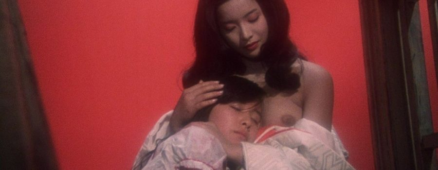 A young Asian woman in a white bridal gown cradling the head of another young Asian woman who rests on her chest.
