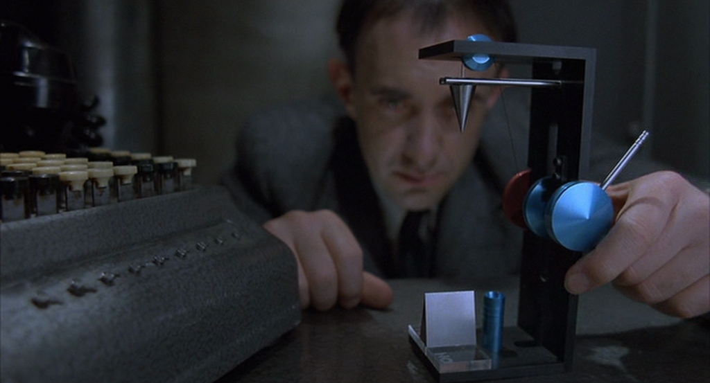 Sam Lowry (Jonathan Pryce) fiddles with an unnecessarily complex paperweight at work.