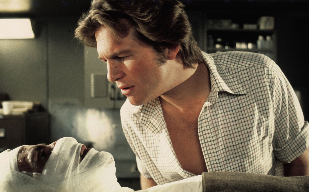 Jeff Bridges scrutinizes the face of a heavily bandaged man, from the film Winter Kills. 