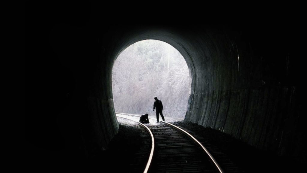 Detective Seo confronting a suspect on train tracks, at gunpoint, in front of a tunnel.