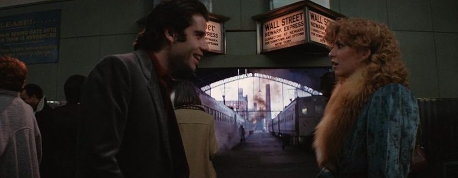 Jack, a young light-skinned man with dark hair, and Sally, a young woman with blonde curly hair, are standing on a train starting platform facing each other, with side characters and trains in the background.