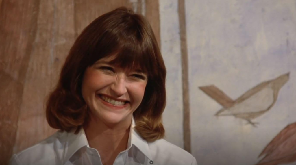 Jan Hooks smiles widely as Tina the tour guide