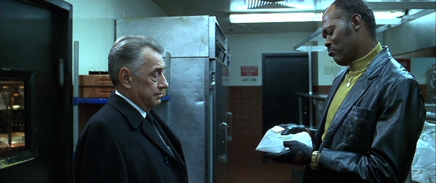 Philip Baker Hall and Samuel Jackson facing each other, with Samuel L. Jackson examining the contents of an envelope.]