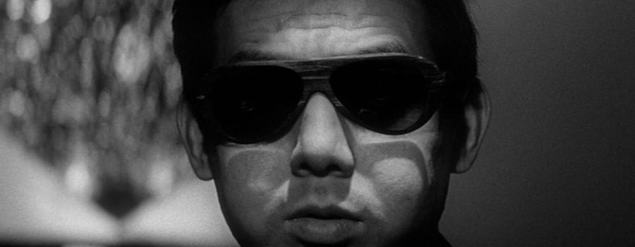 A black and white image of an adult man with dark hair wearing sunglasses