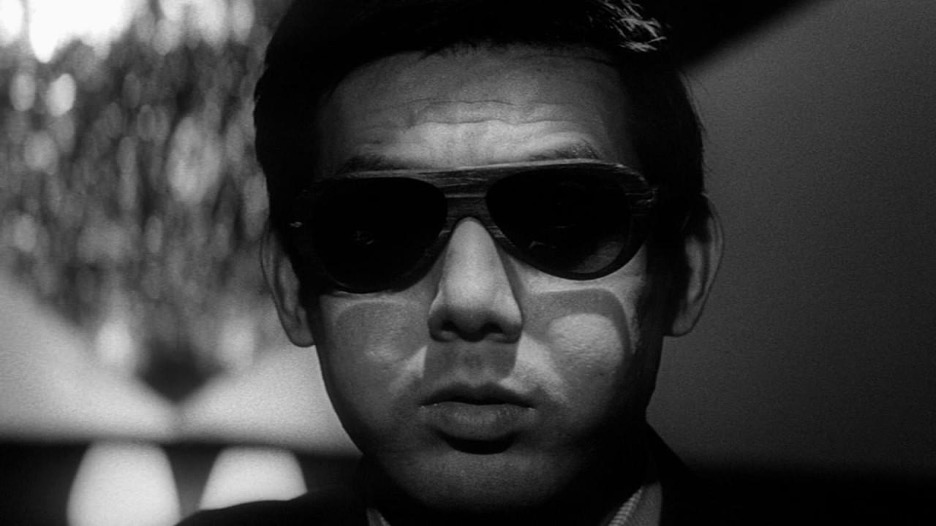 A black and white image of an adult man with dark hair wearing sunglasses