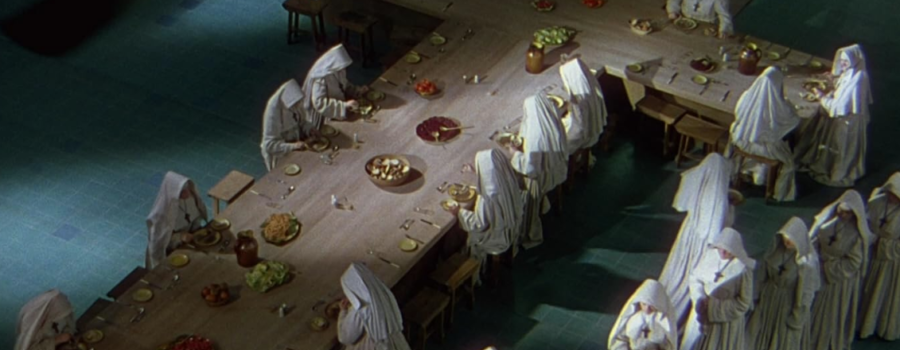 Nuns sit for dinner at a cross-shaped table.