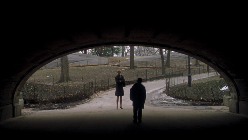 Nicole Kidman stands in a park looking into a dark tunnel. Opposite her is the silhouette of a child standing inside the tunnel.