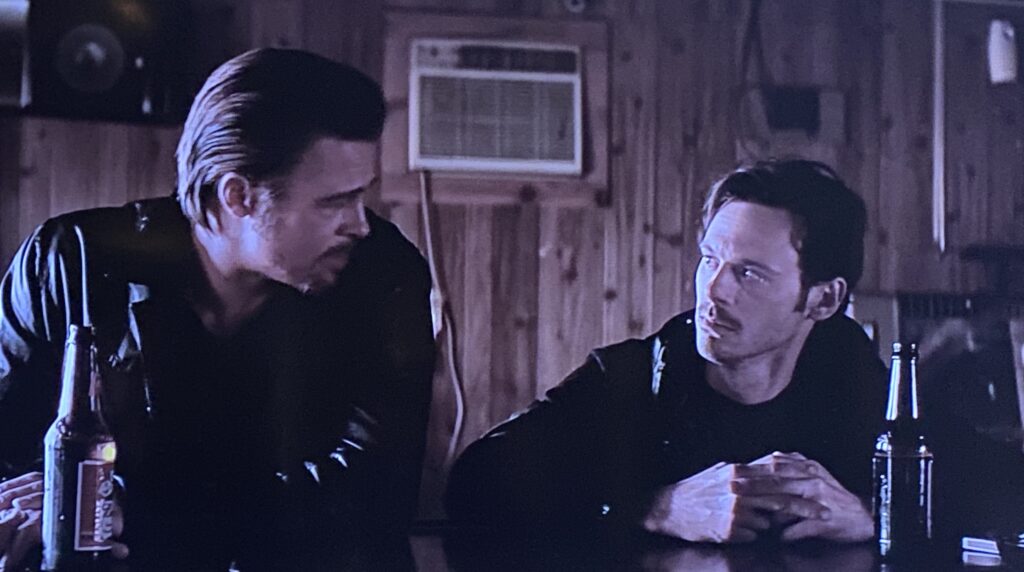 Two men drinking side by side at the bar of a working-class tavern.