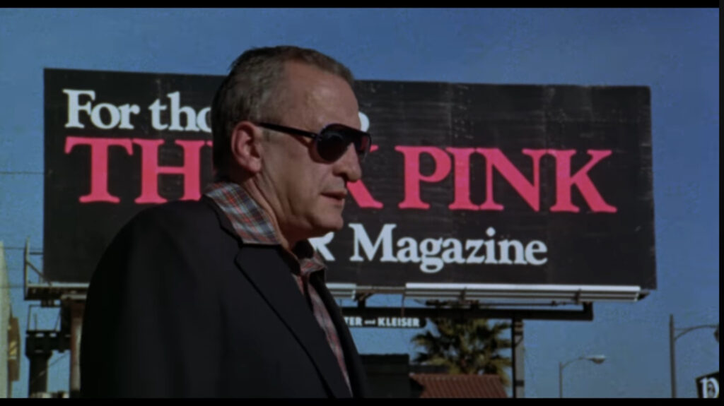 Jake (George C. Scott) stands in front of a Hustler billboard.
