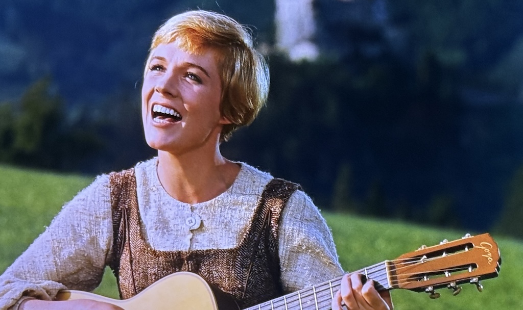 Julie Andrews as Sister Maria playing guitar and singing from a scene in The Sound of Music