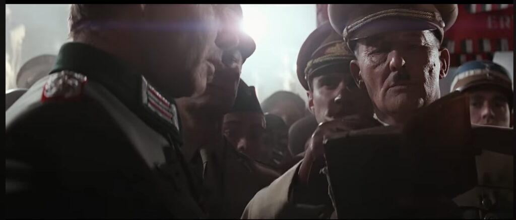 Harrison Ford as Indiana Jones disguised as a Nazi encounters Adolf Hitler who is signing the Grail Diary.