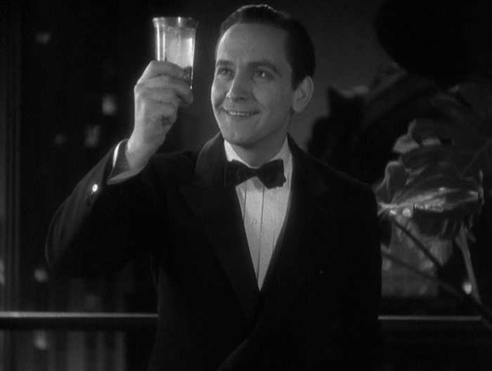 Jerry (Fredrick March) holding a glass at eye level, like he's about to make a toast. He stares at it happily.