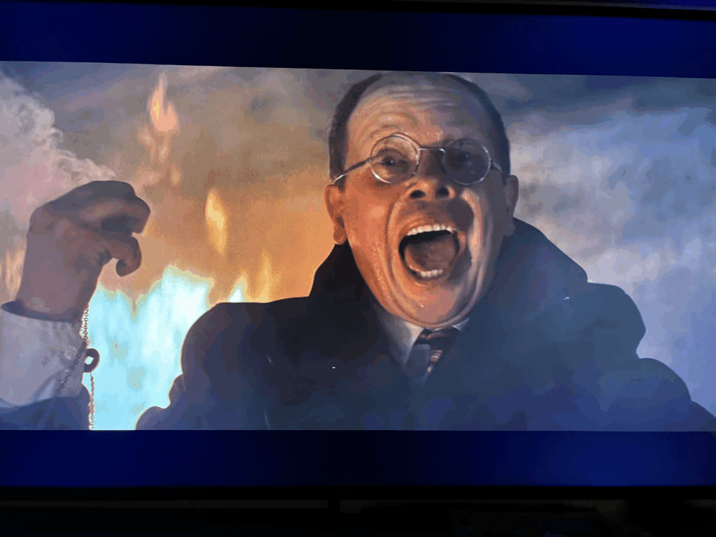 Ronald Lacey as Major Toht screams with burnt hand held high in pain.