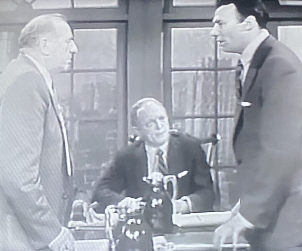three businessmen stand at a conference table in an executive meeting room.