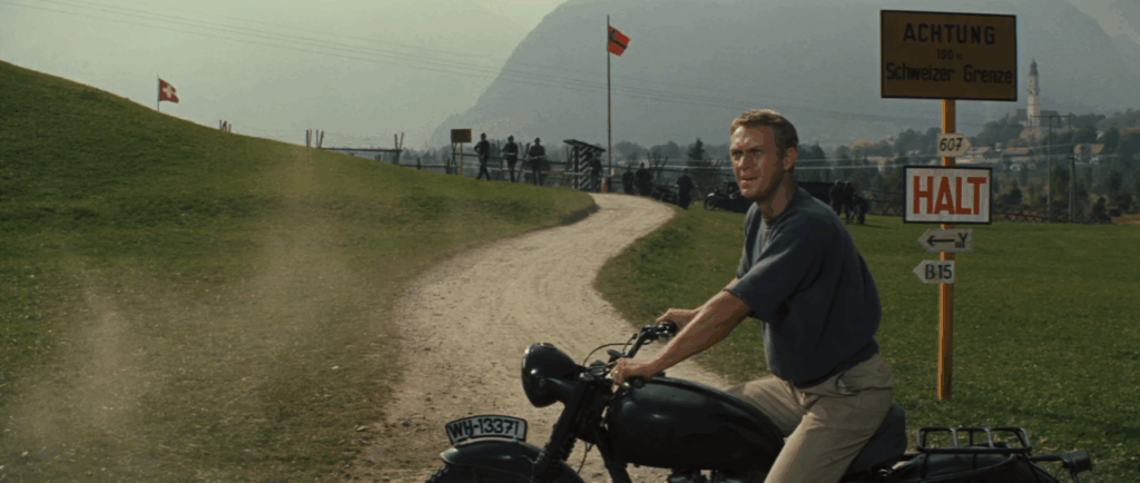 Shot of Steve McQueen on a motorcycle with German soldiers in the background