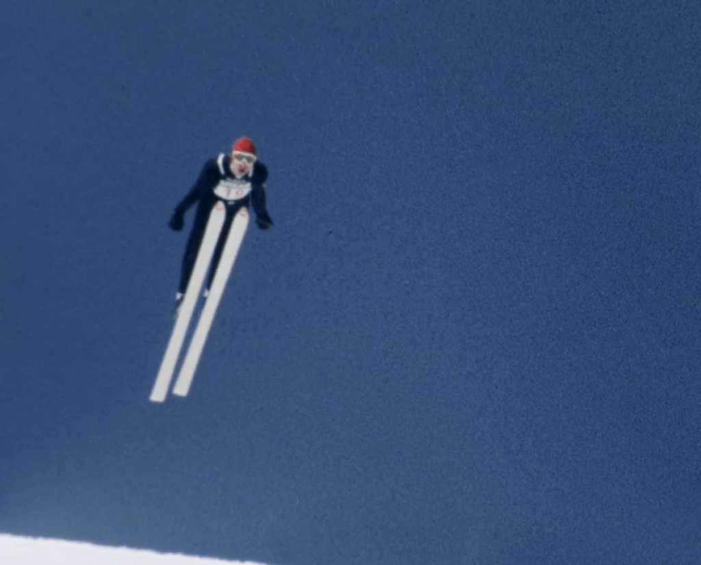 A skier flies through the air against the background of a clear blue sky.