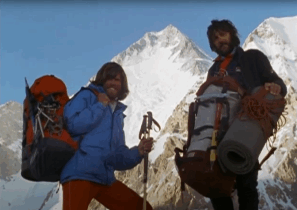 Reinhold Messner and Hans Kammerlander smiling in front of the camera wearing mountaineering gear