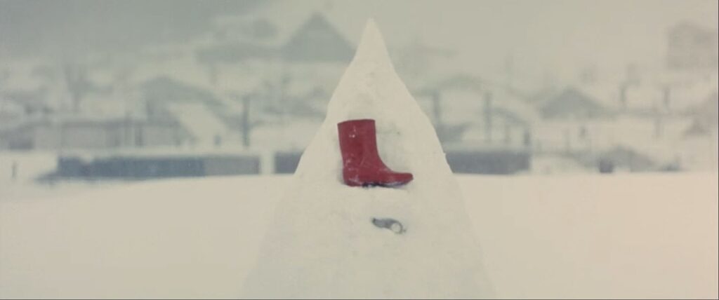 a red snow boot sitting in a pile of snow.